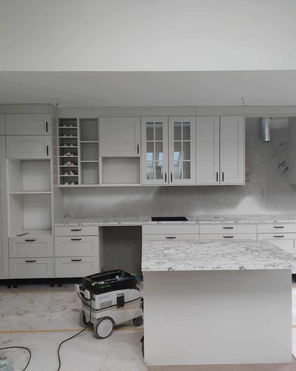White kitchen cabinetry and island mid-installation
