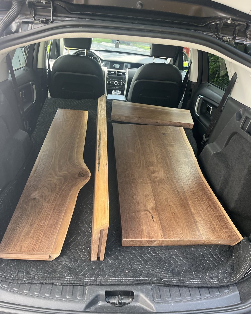 Two raw live-edge walnut slabs loaded in a vehicle