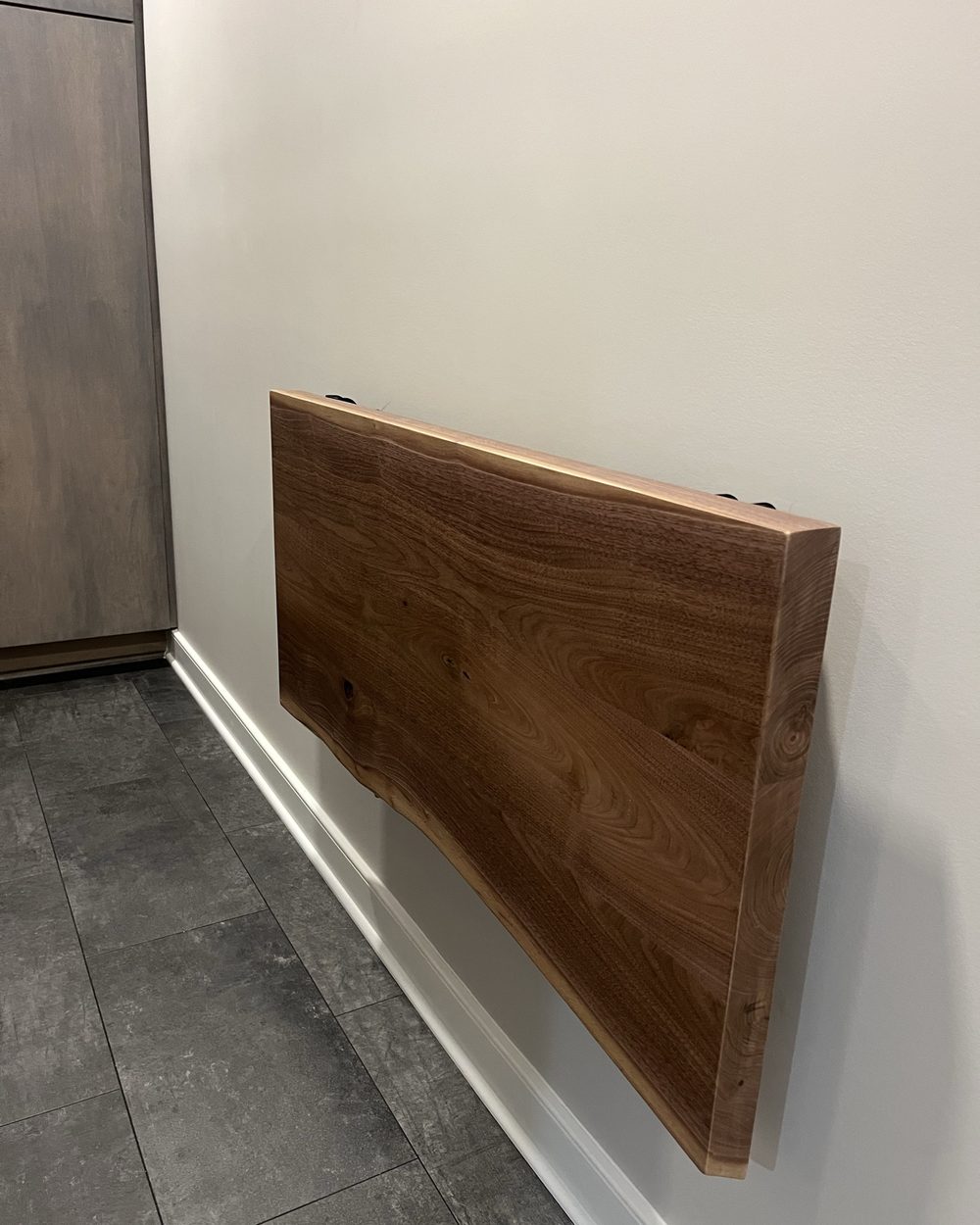 The finished walnut table folded flat against the wall
