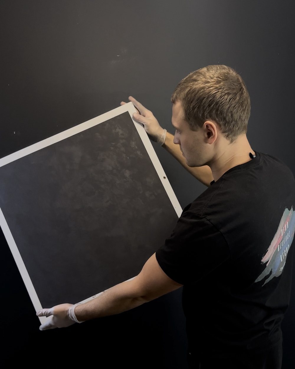 Craftsman holding a large charcoal plaster sample board in the studio