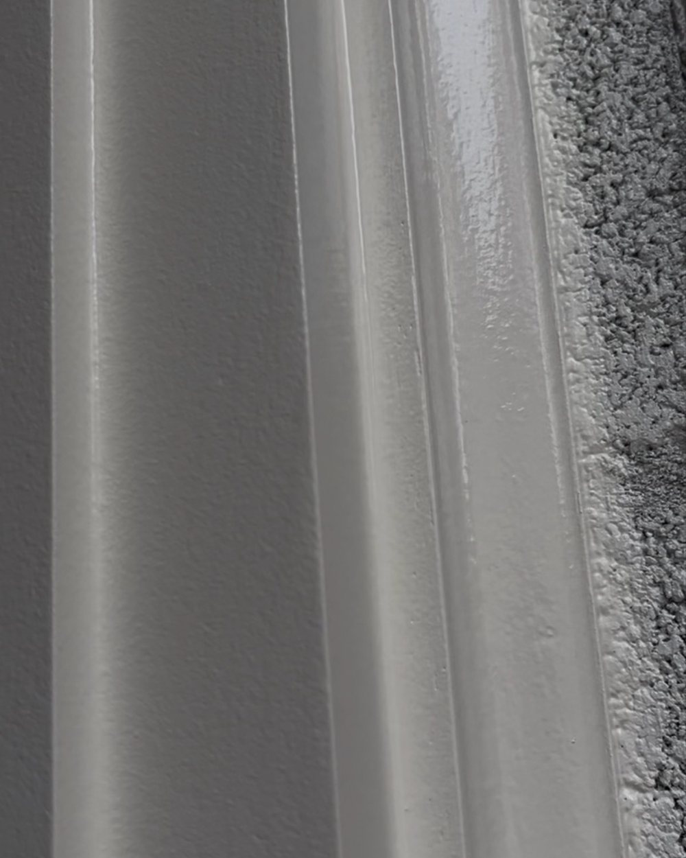 Close-up of a hand-built layered crown molding profile against a textured ceiling