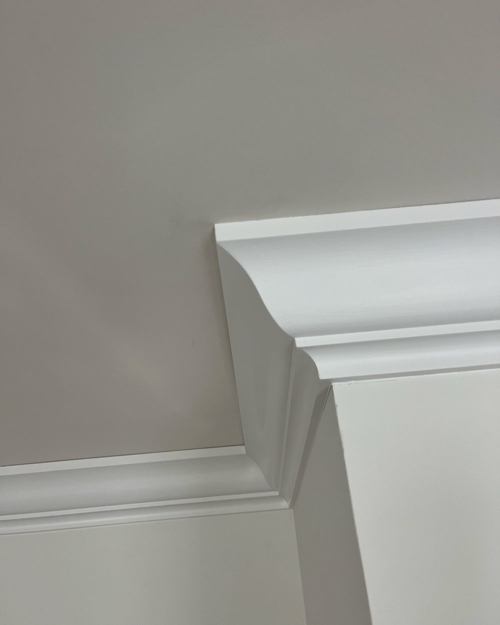 Close up of installed crown molding against a warm gray wall